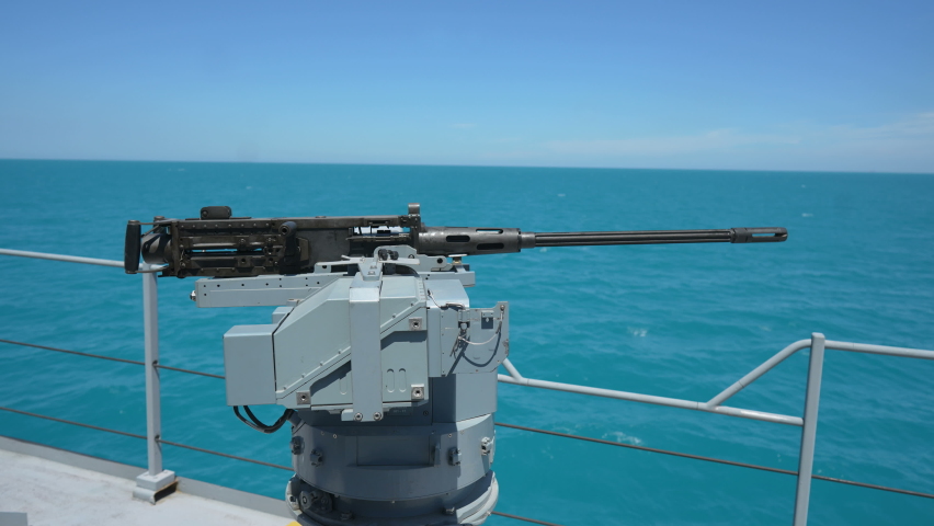 Color image of an automated machine gun on the deck of a military ship, at sea.