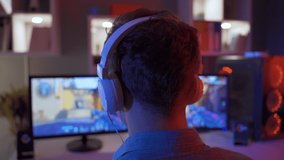 Professional Gamer Playing First Person Shooter Online Video Game on Powerful PC.
Young boy playing a game sitting in front of a computer, wearing headphones.

