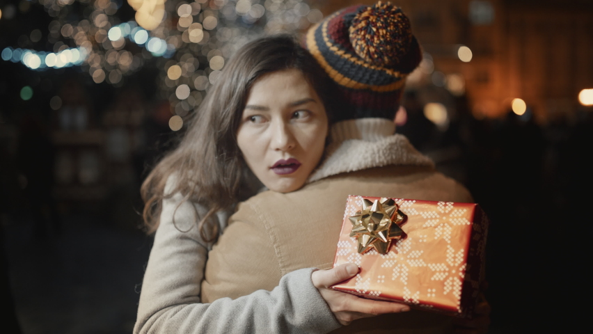 Celebrating New Year holidays vacation. Young man present gift to his girlfriend at decorated town square. Woman unhappy and disappointed. Girl dislike presents. Christmas fail. Unwanted useless thing | Shutterstock HD Video #1096583697