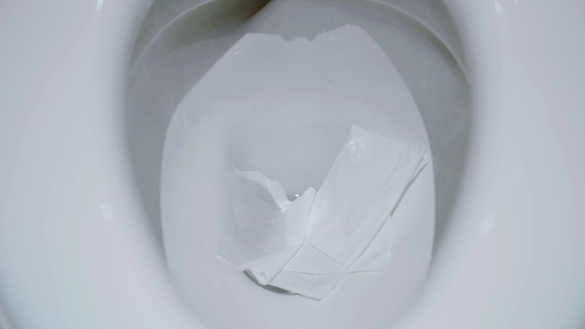 The flushing of toilet tissue paper down a bathroom toilet, water with paper flushing down into the toilet bowl in bathroom. Royalty-Free Stock Footage #1096600951