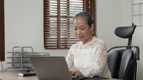 Video of senior woman working on laptop computer.
