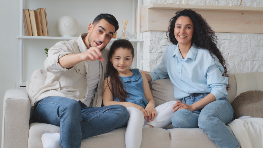 Multiracial family multiethnic Hispanic Caucasian Arabian Indian parents mother father with daughter child girl sitting on couch at home waving hands hello talking on online video call chat conference Royalty-Free Stock Footage #1096606113