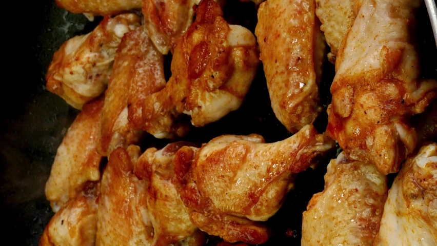 Many sprinkled with spices sliced chicken wings, preparation and turning in hot frying pan. Royalty-Free Stock Footage #1096609397