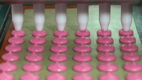 Making Multiple Macarons and pink colored macarons from Pink Macaron Shells on a Mat in Close-up on Production Line, Macaron Factory, Food Factory. 4K Video shooting.
