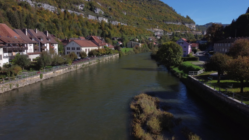 aerial shot over the river and the bridge of the city st-Ursanne on a sunny day. In Switzerland.