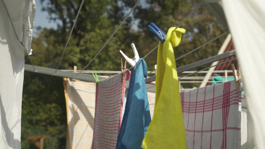 Clothing Hung On Clothesline Outdoor Secured With Clothespins. Drying Fabric Under Sunlight. closeup