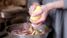 peeling potato with a knife in a bowl in the kitchen with people stock video stock footage