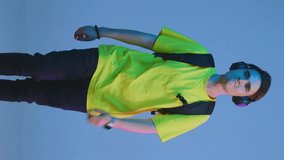 Vertical video of a student, college member walking, dancing, enjoying. Guy wears yellow t shirt, backpack and earphones.