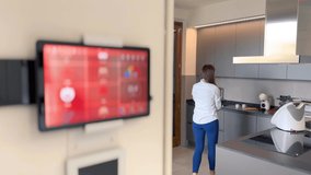 Smart Home Concept. Tablet shows smart home icons in a modern house interior with woman working in the kitchen - Powered by Shutterstock - Get 15% off with code: PIKWIZARD15