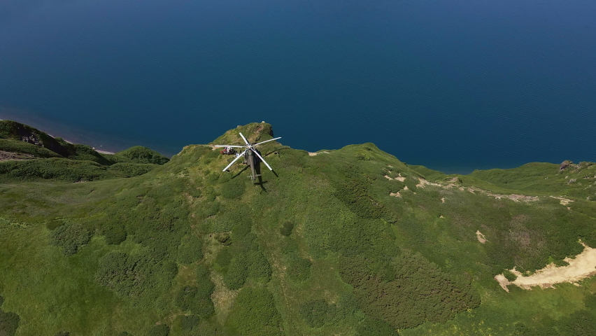 Helicopter standing on the edge of Krenitsyn volcano. Volcano in a volcano. Kuril Islands. Onecotan island. Tourist attraction in Kamchatka
