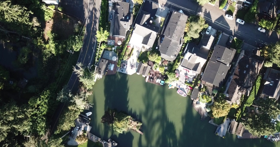 Pan over beautiful Lake Oswego, Oregon, which is just south of Portland. Lush forests line the lake in the early morning sunshine.  Tall pine and sequoia trees are interspersed with lakefront homes.