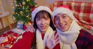 asian lovely young couple wearing christmas clothes are having video chat with friends at home