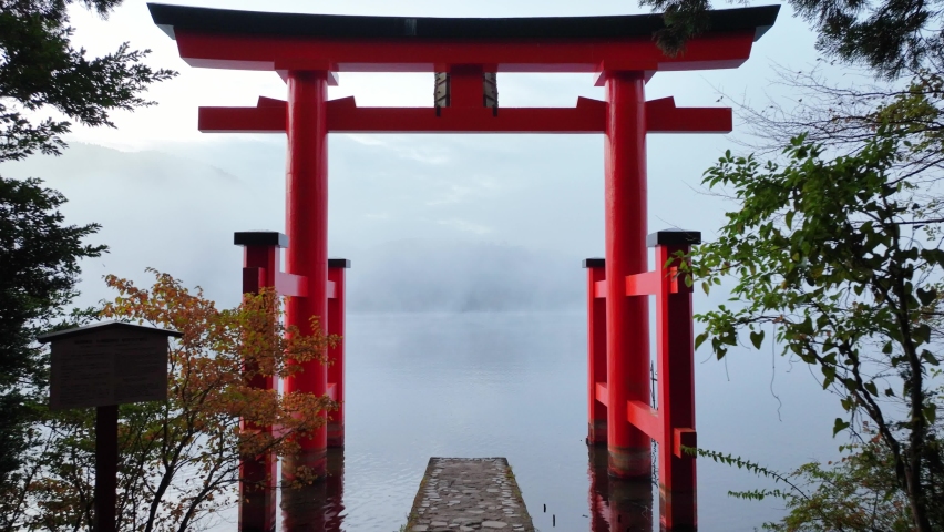 Japanese culture, shinto shrine on Hakone lake, flying through traditional torii gate on a foggy morning, sacred place in Japan | Shutterstock HD Video #1096645953