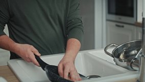Tilt up of adult caucasian man with down syndrome washing dishes at home. Shot with RED helium camera in 8K.   