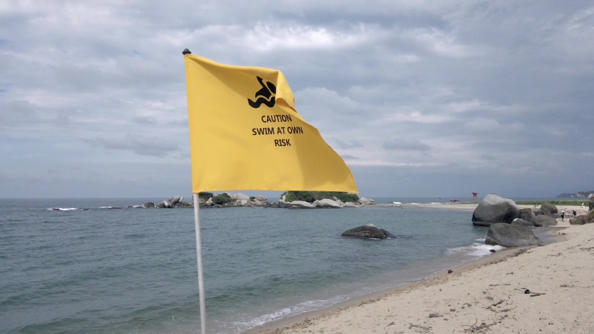 yellow flag indicates prohibition of bathing in the ocean sea, danger of swimming at your own risk in Caribbean Sea beach , Santa Marta Tayrona park Colombia 