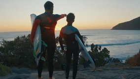 Family surfing. Father and son surfers stand on the coast and watch surfing spot on sunrise - Powered by Shutterstock - Get 15% off with code: PIKWIZARD15