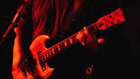 Mens arms plays the red wood electric guitar. Male hands playing electric guitar of rock music. Hands closeup. Red lighting. Man fingers  playing guitar in dark room. Musical background with guitar. - Powered by Shutterstock - Get 15% off with code: PIKWIZARD15