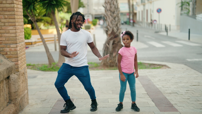 Father and daughter smiling confident dancing together at street