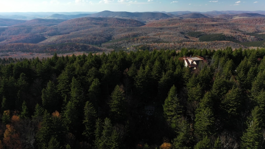 The Seneca Creek Valley in West Virginia is seen in a pedestal-up aerial shot from Spruce Knob, the state high point. An observation tower with unidentifiable people and a road with cars are also seen