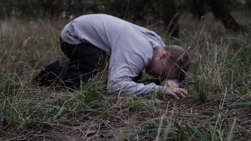 Young man lays on the ground crying and praying