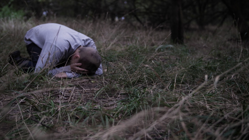 The feet of Jesus Christ approaches a sad, depressed teen boy laying on the ground crying and praying