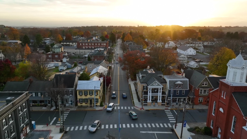 American small town in autumn sunset. Church and restored historic homes as traffic drives by.