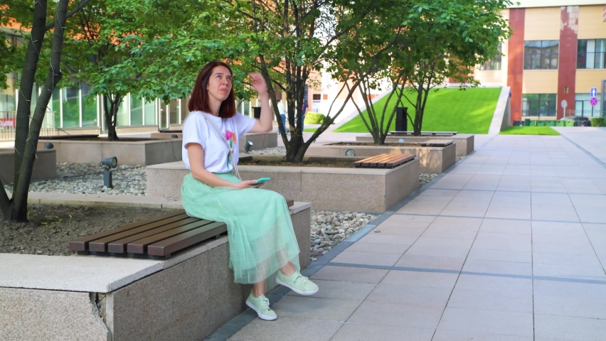 Young woman sitting on a bench and waiting for someone. 4k video footage in slow motion