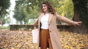 Happy woman in coat holding shopping bags, autumn shopping sale.