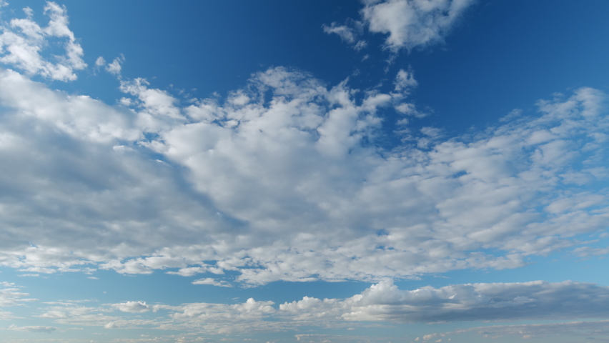 Sky with bautiful silky clouds. Puffy fluffy cumulus and cirrocumulus on different layers clouds. Timelapse.