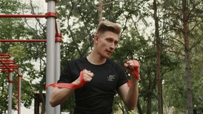 Athletic young fit man warm up by stretching fitness workout a resistance band before exercise at the calisthenics gym outdoors