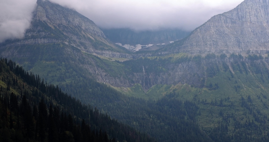 beautiful landscape in Glacier National Park Montana in stormy winter conditions with a distant waterfall from the melting glacier just above