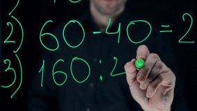 a male teacher writes a mathematical formula on glass with a neon felt-tip pen