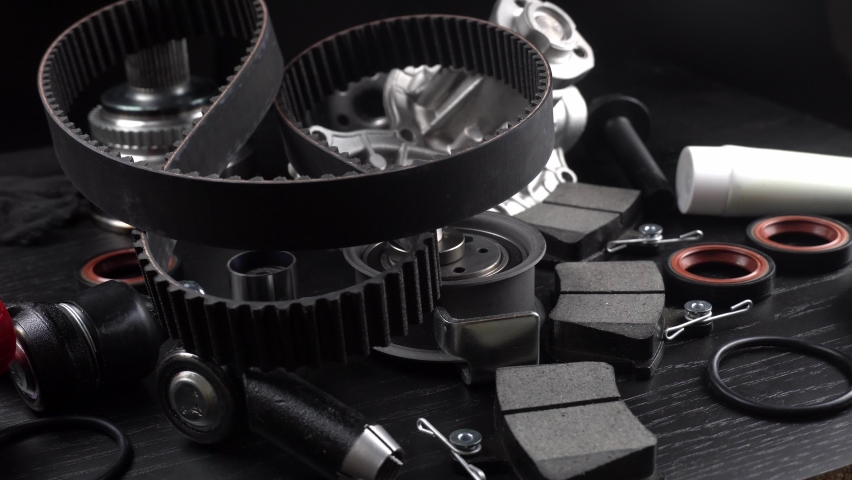 Lot of auto parts lie on wooden black background. Engine and suspension parts, swivel knuckle, joint and engine parts unfolded. New spare parts. Bearings . Play by light. Hanging on table. Royalty-Free Stock Footage #1096697059