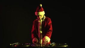 Santa claus dj playing music on new year celebration in night club. Disc jockey wearing red Christmas outfit plays set on xmas party in nightclub