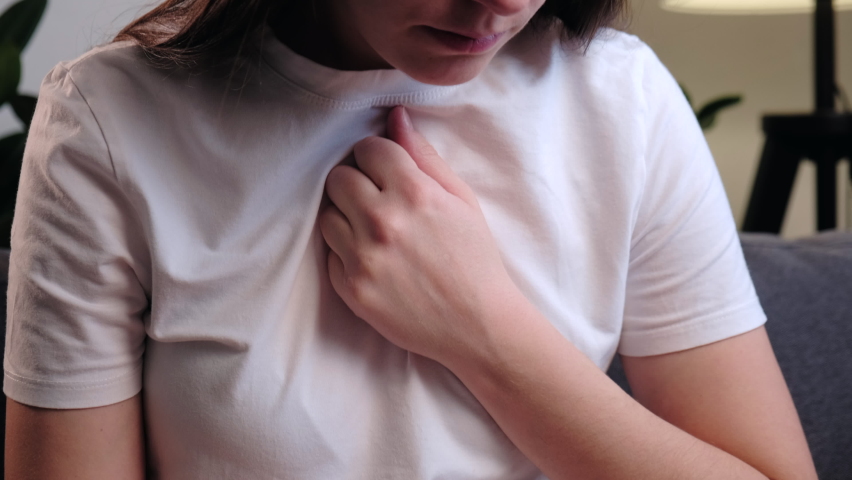 Trouble breathing, chest pain. Young unhealthy woman sit on sofa having difficulty breathing pain of heart, touches his chest with hand. Heart attack, thoracic osteochondrosis, panic attack concept | Shutterstock HD Video #1096712007
