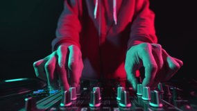 Dj playing music on sound mixer in night club. Dynamic video clip of disc jockey filmed with shaking camera in 4K. Download stock footage of disk jokey mixing set on stage in nightclub