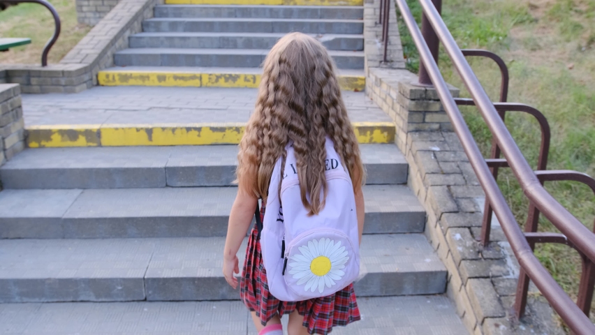 A teenage girl with a backpack climbs the concrete steps of the stairs