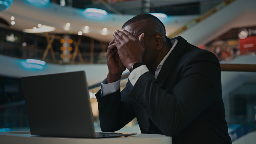 Stressed African American adult middle-aged mature man worker with computer suffering from tired exhausted headache painful head overwork with laptop late evening in office employee businessman upset Royalty-Free Stock Footage #1096722037