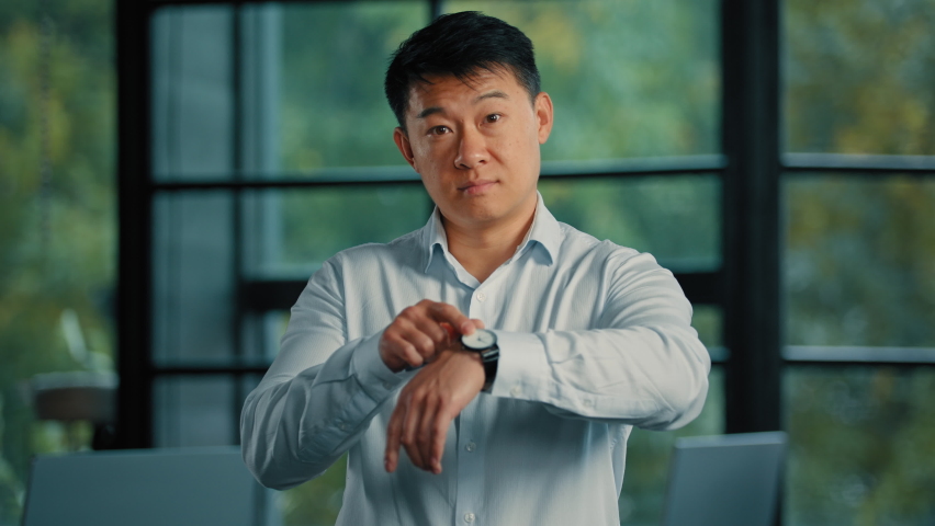 Nervous senior businessman boss employer punctual asian man wait for meeting in office look at wrist watch check time minutes point on luxury clock worried about being late lateness missing deadline Royalty-Free Stock Footage #1096722073