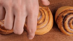 Hand take cinnamon rolls. Freshly baked cinnamon rolls or Cinnabon close up on wooden board - Powered by Shutterstock - Get 15% off with code: PIKWIZARD15