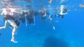 Tourists climbing on ladder from blue ocean underwater video | Tourists climbing in boat after swimming and snorkeling adventure tour in boat |turquoise underwater with clear view of coral reef in Sea