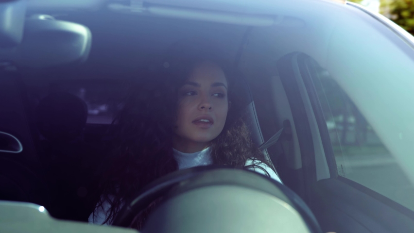 Attractive positive smiling brunette woman inside the car driving spinning steering wheel looking on road. Caucasian young businesslady drives vehicle to work in city. Close up Royalty-Free Stock Footage #1096731931