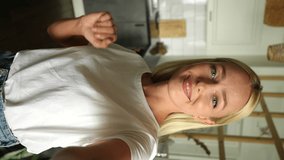 Vertical POV of pretty friendly young woman with blonde hair greeting waving hands and talking making video call, holding in hand smartphone, looking at camera, standing at home kitchen room. - Powered by Shutterstock - Get 15% off with code: PIKWIZARD15