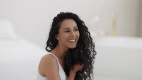 Domestic haircare. Young happy curly woman enjoying condition of her healthy hair, looking at mirror at home and laughing, slow motion, free space - Powered by Shutterstock - Get 15% off with code: PIKWIZARD15