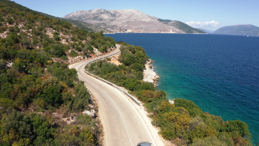 Drone following the car moving by the sea curved road near a tranquille waves on the Greek coast on Cephalonia island. Transportation, nature 4K aerial video concept. Royalty-Free Stock Footage #1096736561