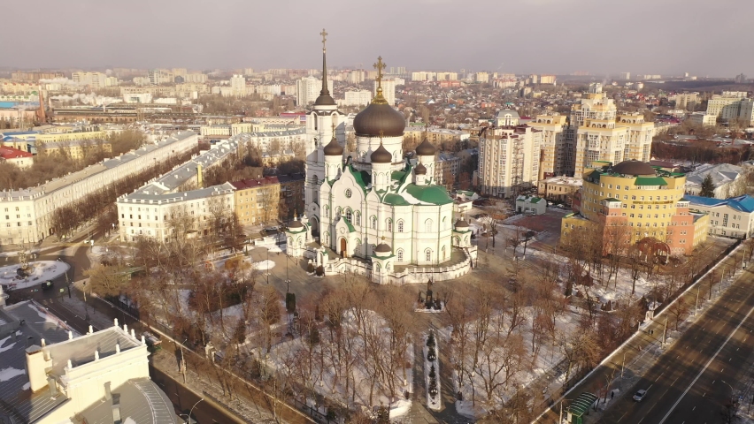 Aerial view of five-domed building of Annunciation Cathedral with attached bell tower in Voronezh on background with winter cityscape, Russia Royalty-Free Stock Footage #1096743913