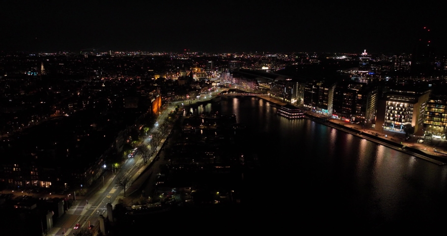 Amsterdam city center skyline by night aerial drone overhead view. Amsterdam Centraal, Ij, Oosterdok, Prins Hendrikkade, public transport, traffic at night. Bright lights urban