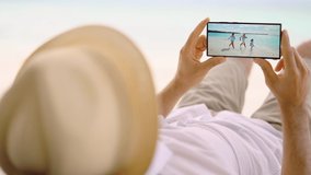 Man Watching TV Film Or Video On Smartphone On Beach