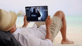 Man Watching TV Film Or Video On Tablet On Beach