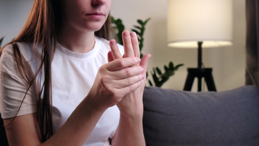 Pain in fingers. Sick young woman with arthritis and joint pain in fingers sitting on couch at home. Close-up of female hand with symptoms of chronic gout. Health care easy self massage concept Royalty-Free Stock Footage #1096753103